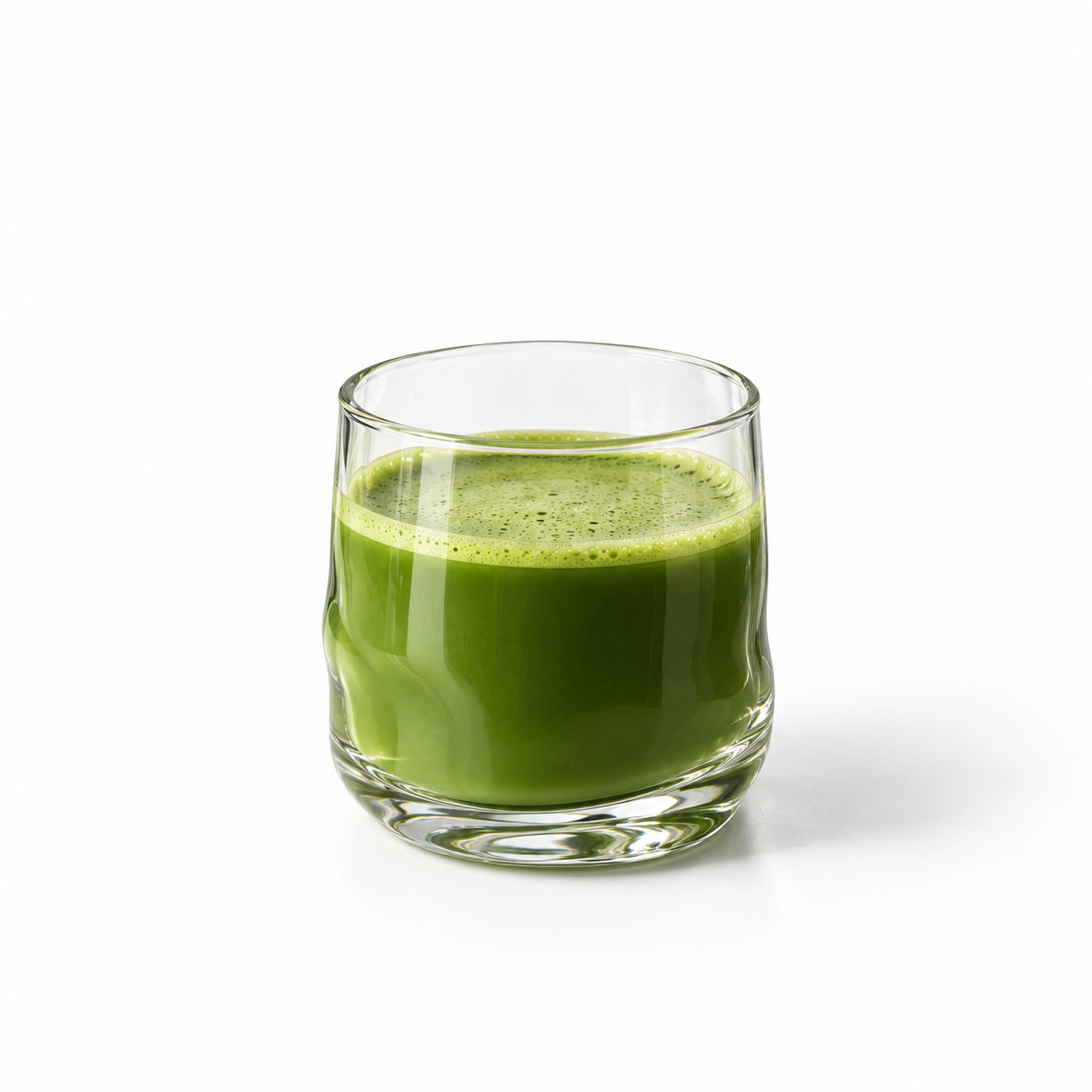 A bowl of whisked matcha beside a bamboo whisk